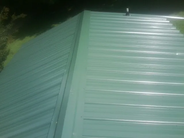 New green metal panels meeting at the ridge of a roof — Flat Roof Repair work by our crew in Mesa