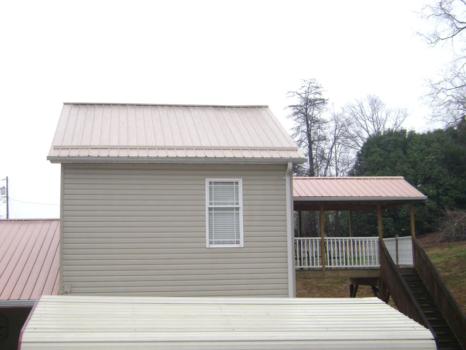 Tan metal roofs on a two story addition and attached porch, from a Roof Replacement job in Mesa